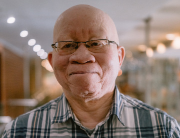 Close-up portrait of South African albinism advocate Patrick Wadula wearing glasses and a checked shirt at the World Forum on Skin Cancer Management in Persons with Albinism in Cape Town.