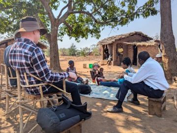 African mother with albinism holding her child outdoors under the sun.